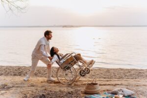 man en vrouw in rolstoel op strand