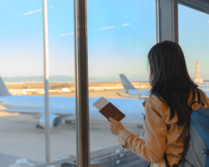 vrouw met paspoort kijkend naar vliegtuig