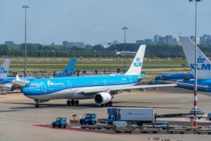 KLM-vliegtuig op Schiphol dat over het platform taxi’t met andere vliegtuigen op de achtergrond.