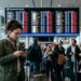 Reizigers op luchthaven kijken naar vertrekbord met meerdere geannuleerde vluchten en naar hun reisverzekering.