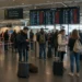 Reizigers wachten met koffers in een drukke vertrekhal na geannuleerde vluchten door een staking.